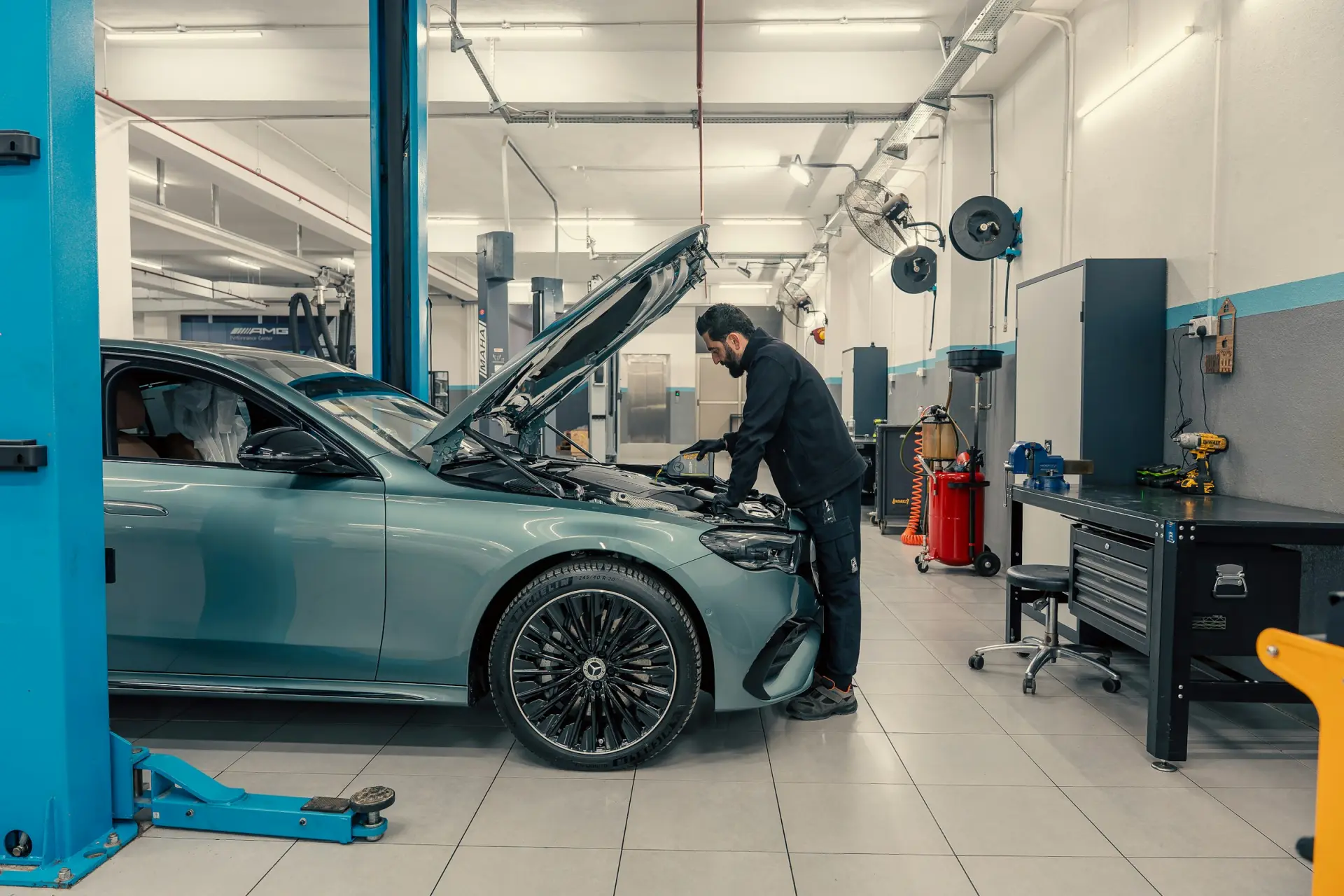 A technician working under the hood of a car on a lift